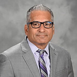 a man in a suit and tie standing in front of a gray background
