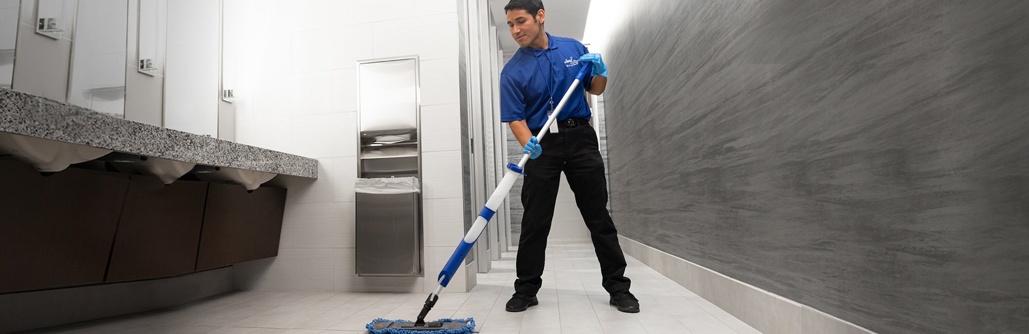 a man in a blue shirt and black pants is cleaning a bathroom