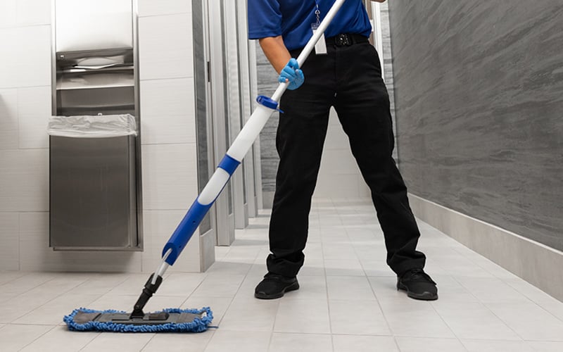 a man in a blue shirt and black pants is cleaning a bathroom