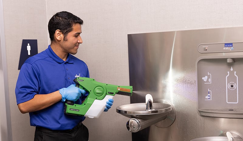 a man disinfecting the water fountain area