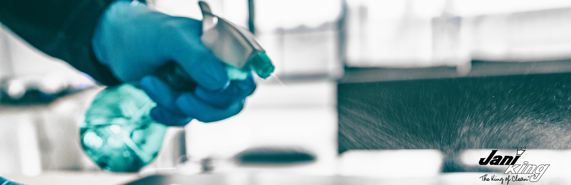 Employee spraying a hard surface in a business setting.